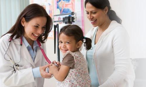 Nurse Practitioner Smiling with Child Patient Taking Heart Rate 